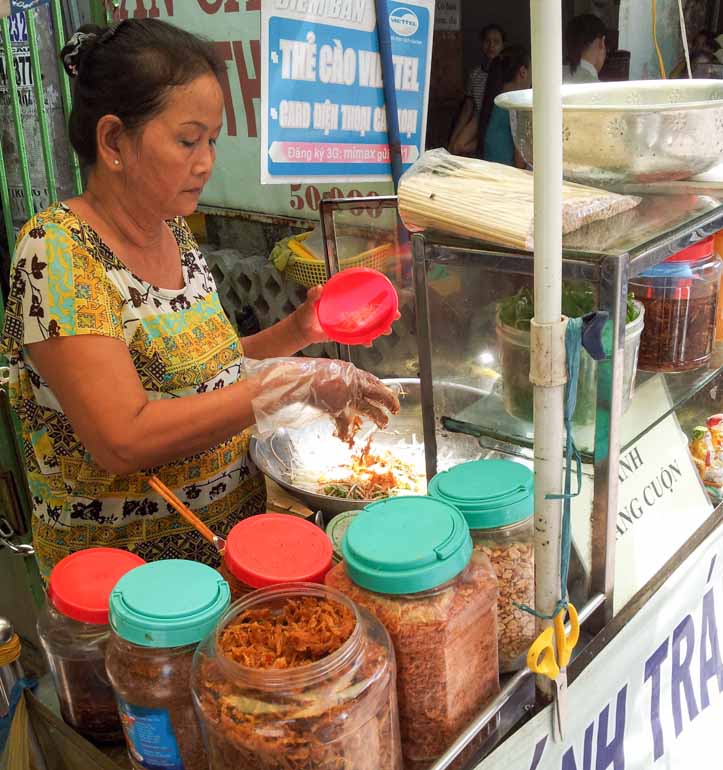 Lady preparing banh trang tron at a street food stall in Vietnam
